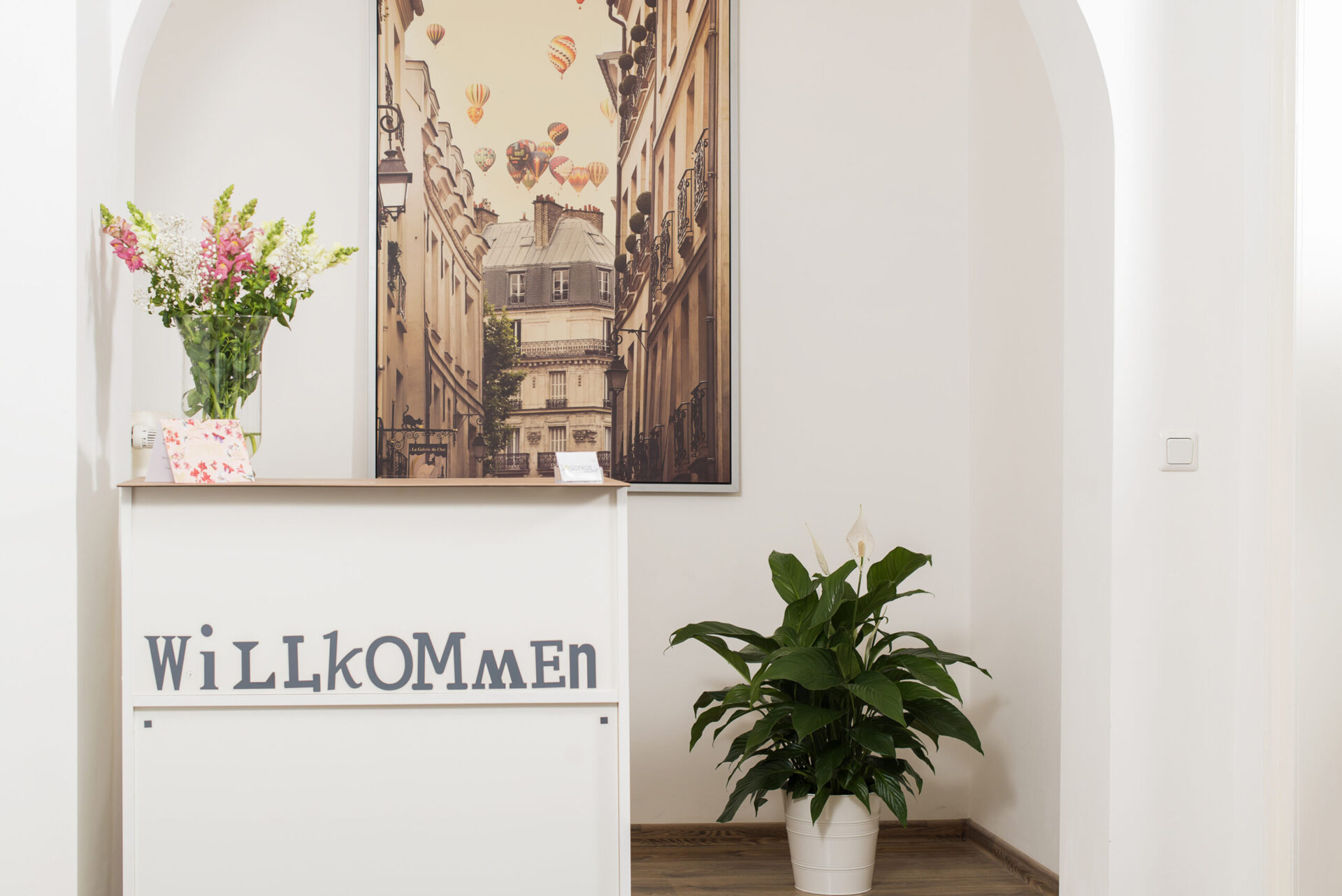 Heller Eingangsbereich mit einem großen Schild auf welchem "Willkommen" steht.